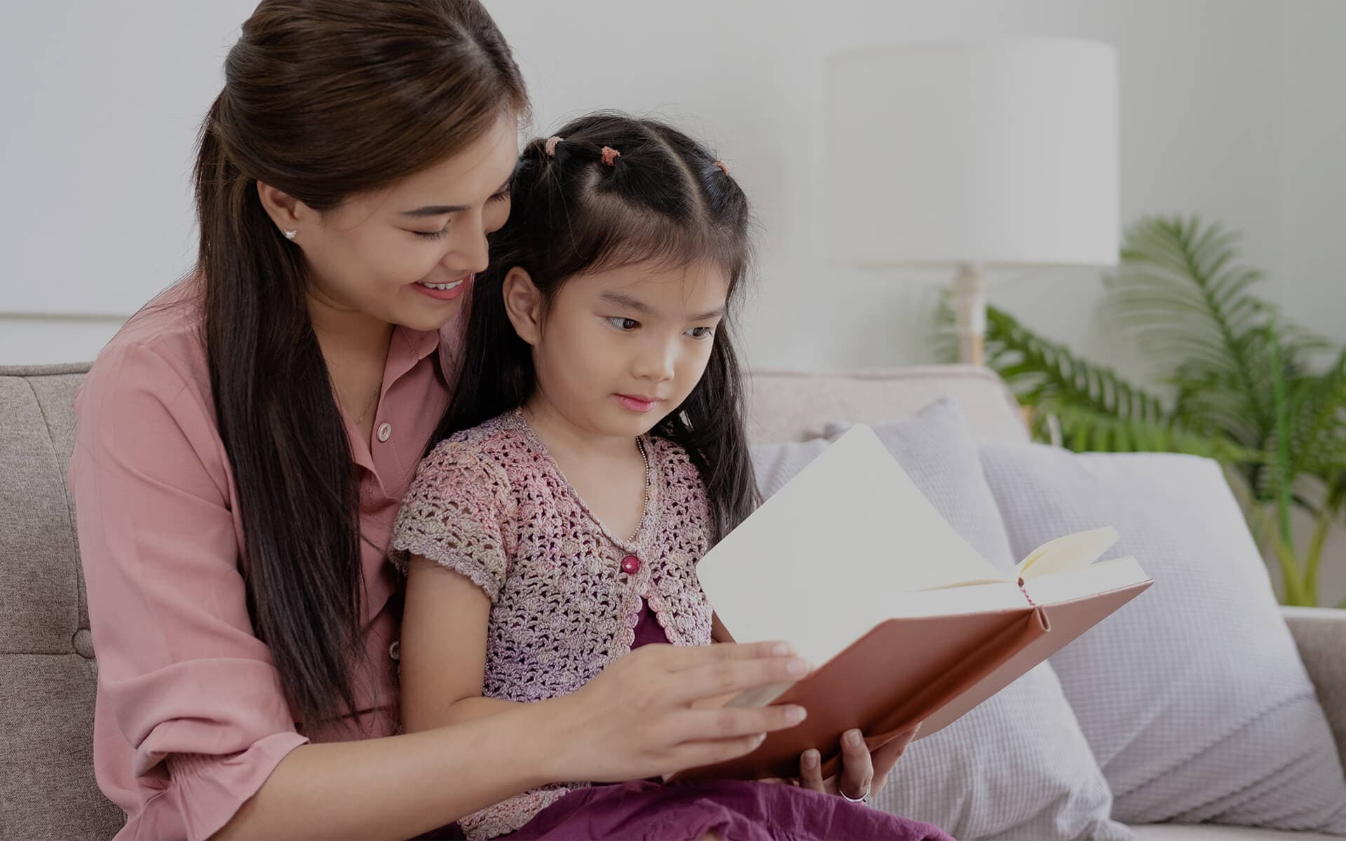 Koltukta çocukla birlikte kitap okuyan bakıcı